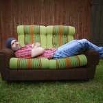 young self reliant man lying on a couch in the outdoors