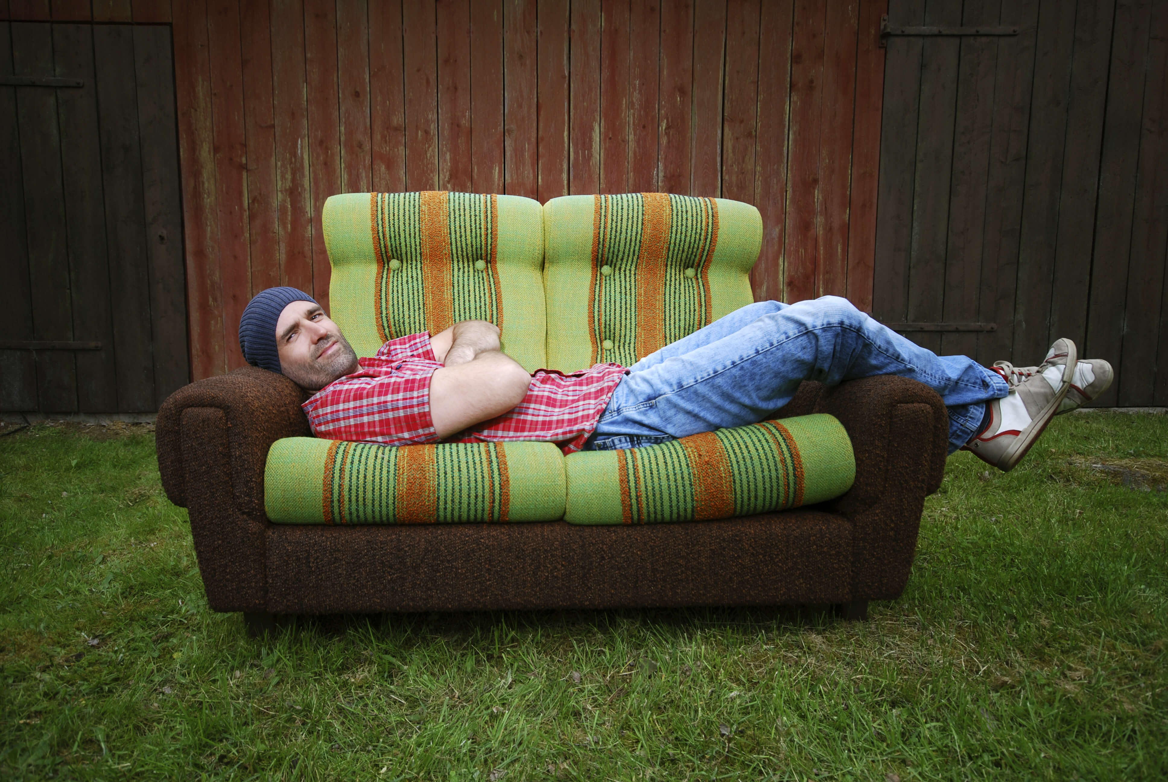 young self reliant man lying on a couch in the outdoors